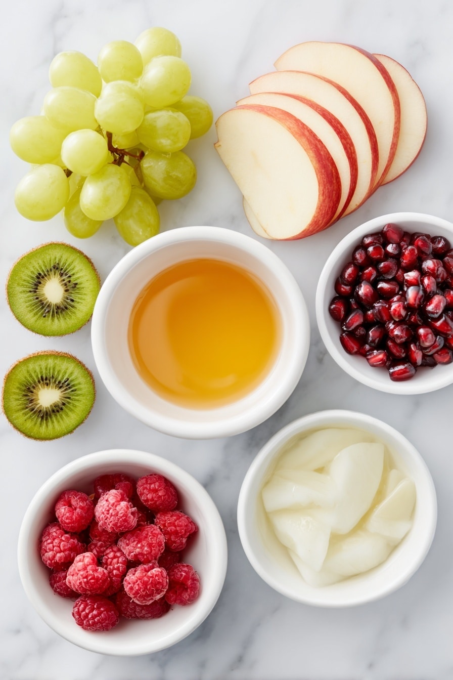 Flat lay of a sliced Granny Smith apple with bright green flesh and crisp skin, a sliced red apple with vibrant red and white contrast, a small cluster of fresh green grapes, a small cluster of fresh red grapes, two peeled and sliced kiwi showing vivid green flesh with black seeds, a handful of plump red raspberries, a small pile of shiny pomegranate arils, a small white ceramic bowl filled with golden honey, a small white ceramic bowl with fresh lime juice, a small white ceramic bowl of clear water, all arranged in perfect symmetry, placed on a clean white marble surface, soft natural light, photo taken with an iPhone, professional food photography style, fresh ingredients, white ceramic bowls, no bottles, no duplicates, no utensils, no packaging --ar 2:3 --v 7 --p m7354615311229779997 - Festive Christmas Fruit Salad, Christmas fruit salad, holiday fruit salad, easy Christmas salad, colorful holiday recipe
