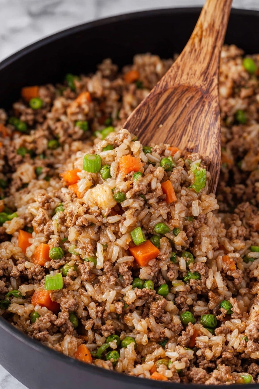 This image shows a close-up of cooked ground meat mixed with rice and chopped vegetables in a black pan. The dish has a mix of brown from the meat and light tan from the rice as the main colors. There are small orange carrot cubes, green peas, and small green onion pieces scattered evenly throughout the dish, adding pops of bright color. A wooden spoon is scooping part of the mixture from the pan, with the spoon’s wood grain clearly visible. The background is a white marbled texture. photo taken with an iphone --ar 2:3 --v 7 - Skillet BBQ Beef and Rice Dinner, easy BBQ beef skillet recipe, quick beef and rice skillet, one-pan BBQ beef recipe, hearty skillet dinner