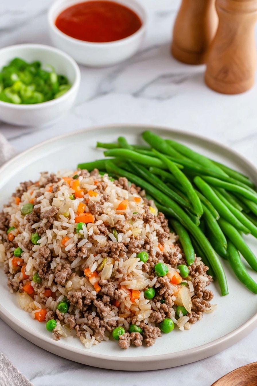 On a white plate sitting on a white marbled surface, there is a serving of fried rice mixed with ground meat, small green peas, finely chopped orange carrots, and bits of onions spread out in a loose mound in the lower half of the plate. Next to this, on the upper right side of the plate, is a neat pile of fresh green beans with a smooth texture. In the background, there are two small white bowls, one filled with red sauce and the other with green chopped scallions, slightly out of focus. Nearby, a pair of light wooden salt and pepper shakers stand upright. photo taken with an iphone --ar 2:3 --v 7 - Skillet BBQ Beef and Rice Dinner, easy BBQ beef skillet recipe, quick beef and rice skillet, one-pan BBQ beef recipe, hearty skillet dinner